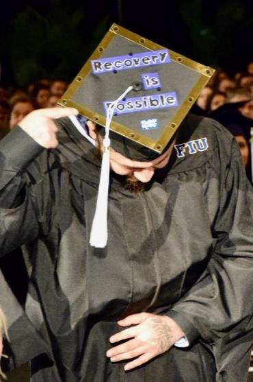 Thomas Guerra wears his cap and gown during the 2018 Summer Commencement, his cap reads "Recovery is possible"